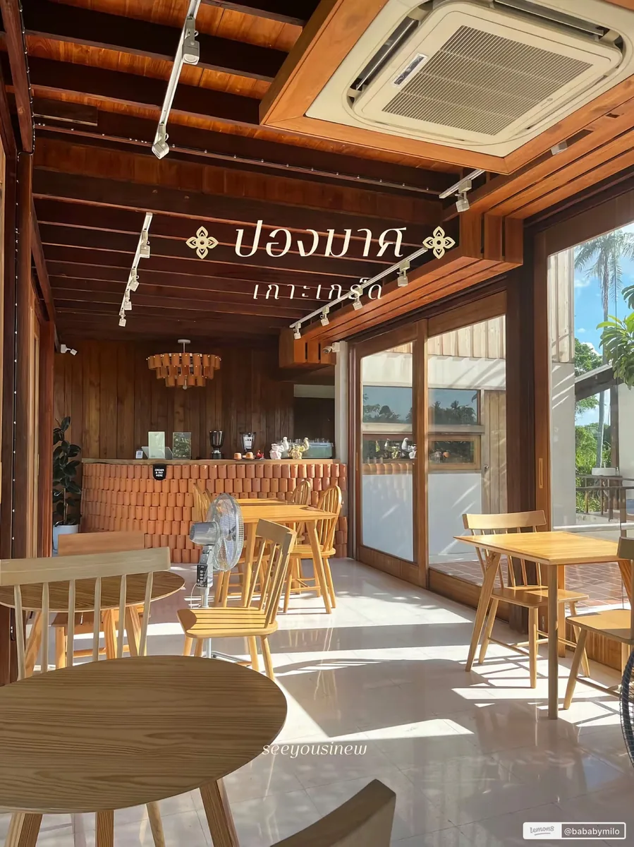 ภายในร้านโทนไม้สีน้ำตาลเข้ม มีตัวอักษรบนคานเขียนว่า ปองมาศ เกาะเกร็ด เคาน์เตอร์สั่งเครื่องดื่มก่อด้วยกระเบื้องดินเผา และโต๊ะเก้าอี้ไม้วางเรียงริมประตูกระจกบานเลื่อน