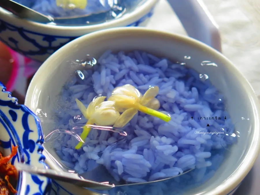 ชามข้าวแช่ ข้าวสวยสีม่วงอมฟ้าแช่อยู่ในน้ำเย็นใส มีดอกมะลิลอยอยู่ด้านบน ใส่ในชามลายครามสีน้ำเงิน
