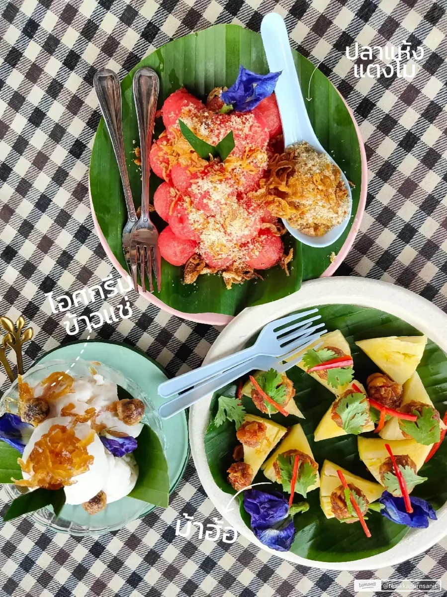 สำรับข้าวแช่จัดเต็ม มีแตงโมปลาแห้งโรยหอมเจียว ไอศกรีมข้าวแช่ในถ้วยแก้ว และม้าฮ่อสับปะรดเสียบบนใบตอง ตกแต่งด้วยดอกอัญชันสีม่วง