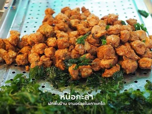 ทอดมันหน่อกะลากองอยู่บนถาดสเตนเลสเจาะรู แทรกด้วยผักใบเขียวทอดกรอบ มีข้อความบนภาพว่าหน่อกะลา ผักพื้นบ้าน จานอร่อยในเกาะเกร็ด