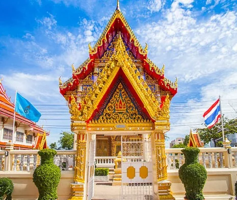 ซุ้มอาคารทรงไทยหลังเล็กในวัด หน้าบันปิดทองประดับกระจกสี หลังคาซ้อนชั้นสีแดงสลับทอง ด้านหน้ามีประตูเหล็กดัดปิดอยู่ ขนาบด้วยไม้พุ่มตัดแต่งทรงกลมสองข้าง มีธงชาติไทยและธงสีฟ้าปักอยู่สองฟาก